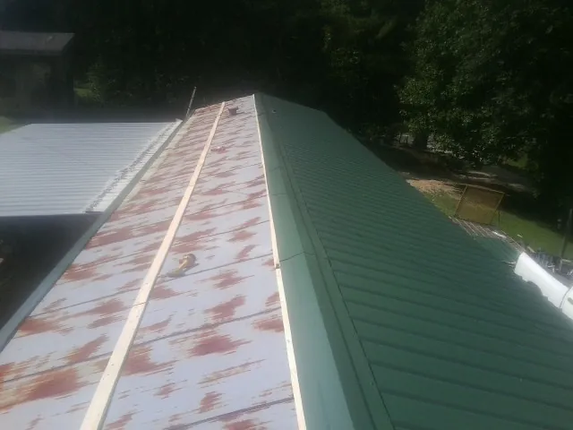 Old rusted panels beside newly installed green metal roofing — Wind Damage Roof Repair by Roofing Brothers in Divernon