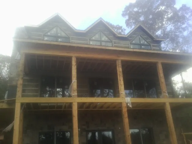 Dormers and porch framing on a large log home under construction — Roof Coating work by our crew in Divernon