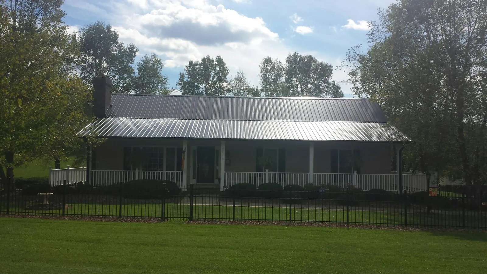 Gray metal roof on a brick ranch with a full width front porch — Gutter Guard Installation work by our crew in Divernon