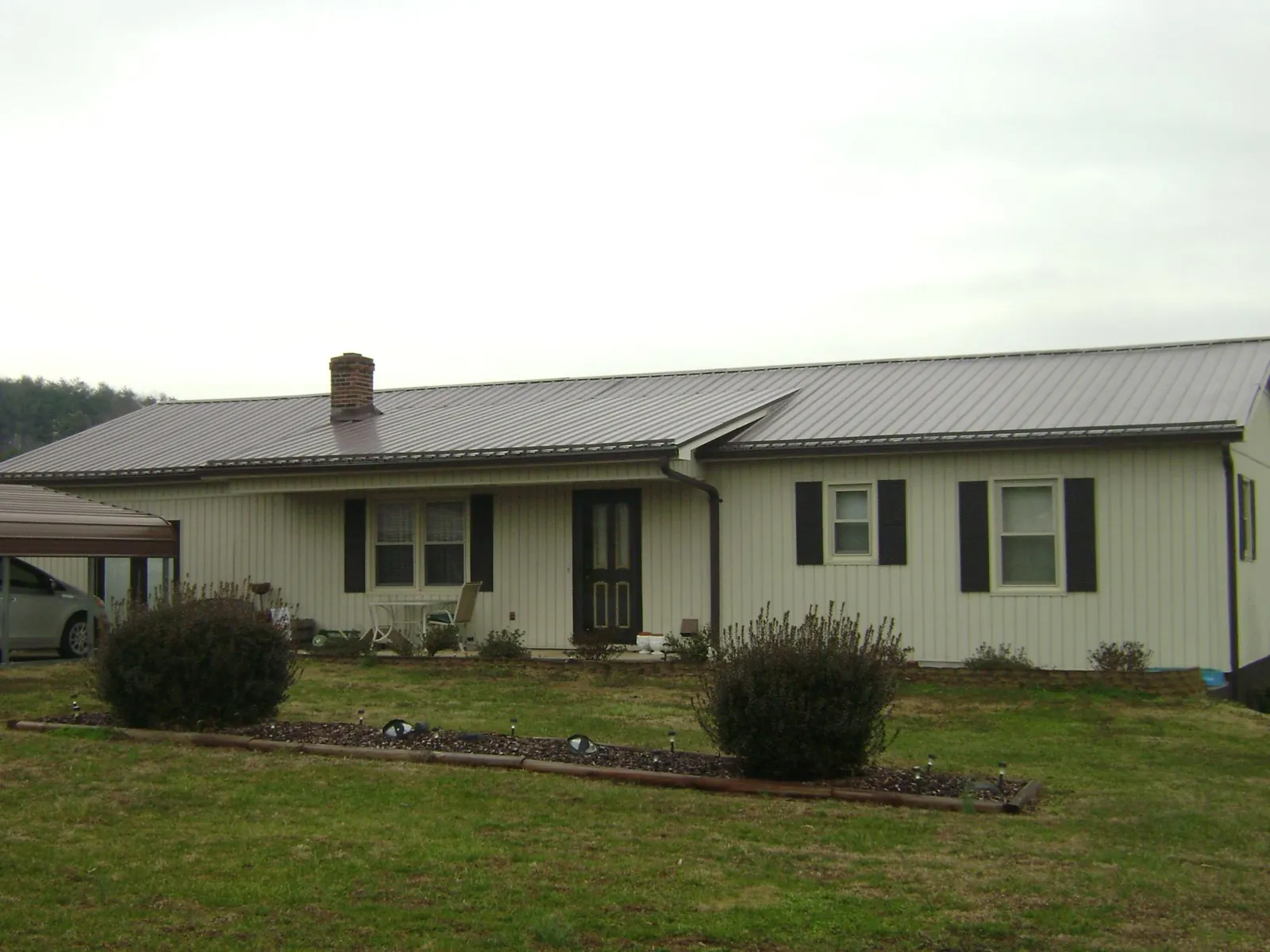 Brown metal roof on a cream sided ranch home with a brick chimney in Divernon