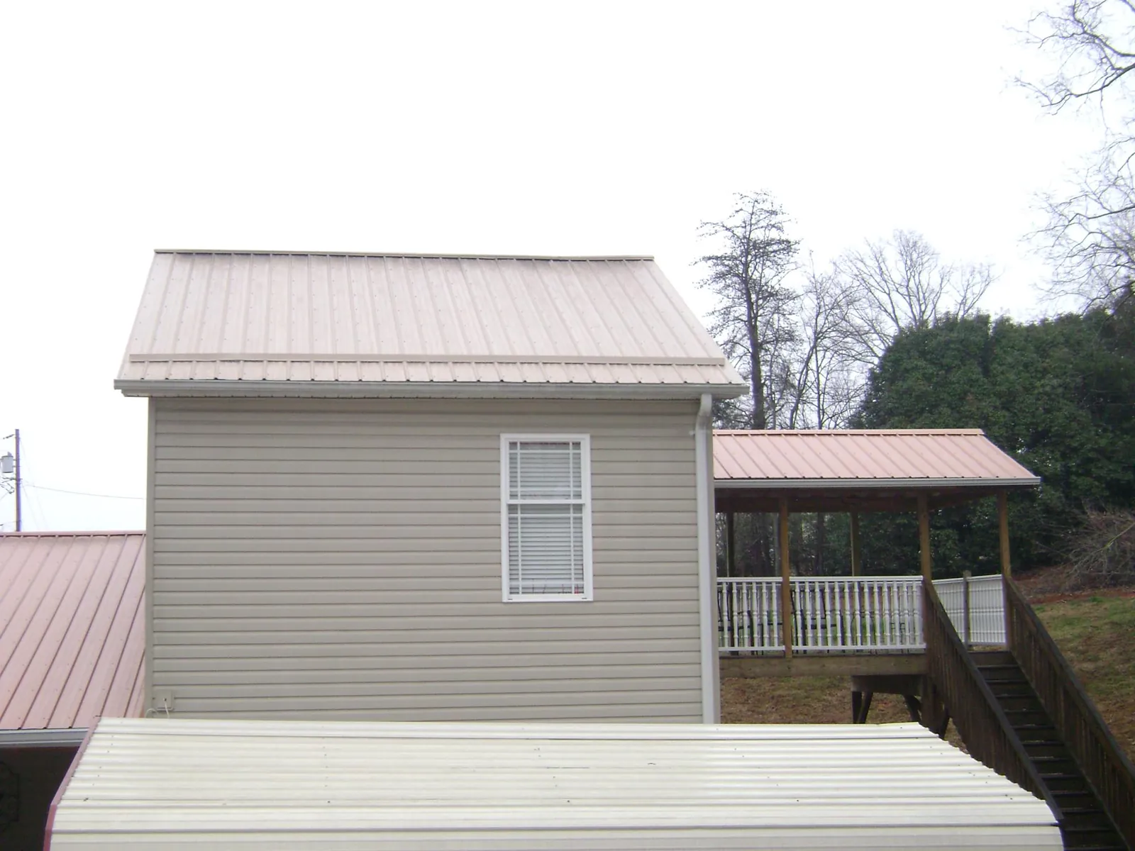 Tan metal roofs on a two story addition and attached porch, from a Roof Replacement job in Divernon