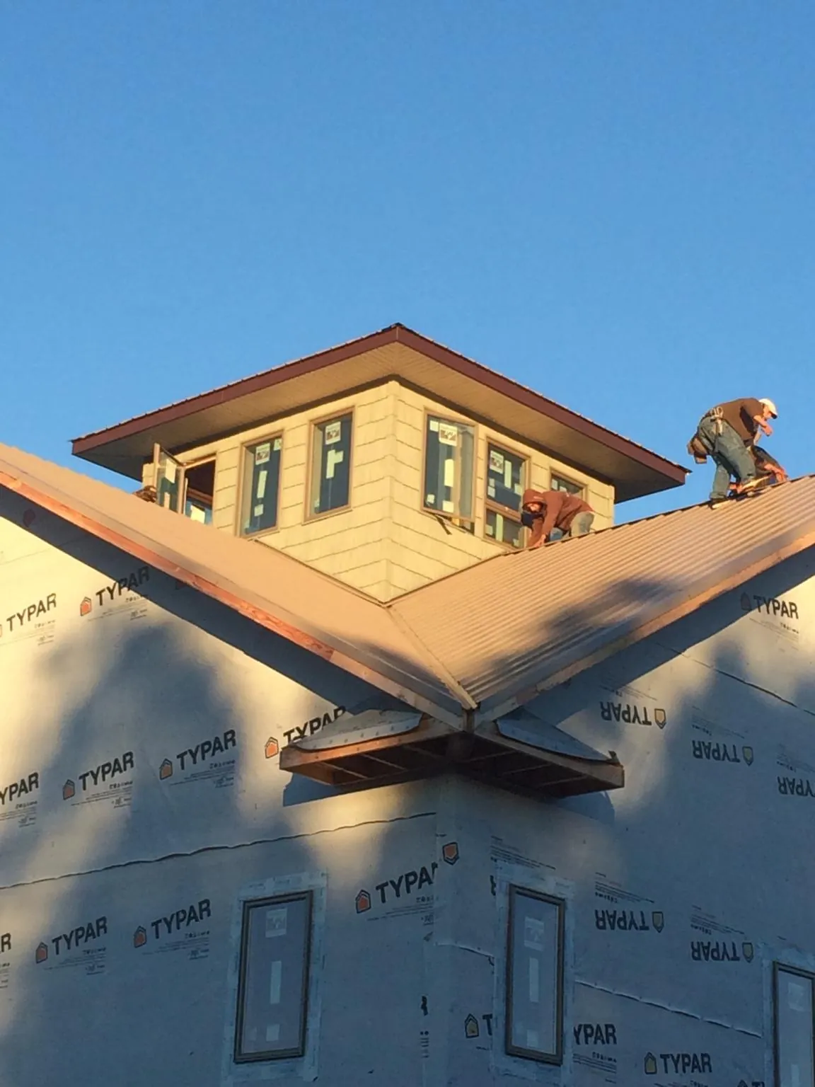 Roofers working around a rooftop cupola on a new metal roof at sunset — Roof Waterproofing in Divernon by Roofing Brothers